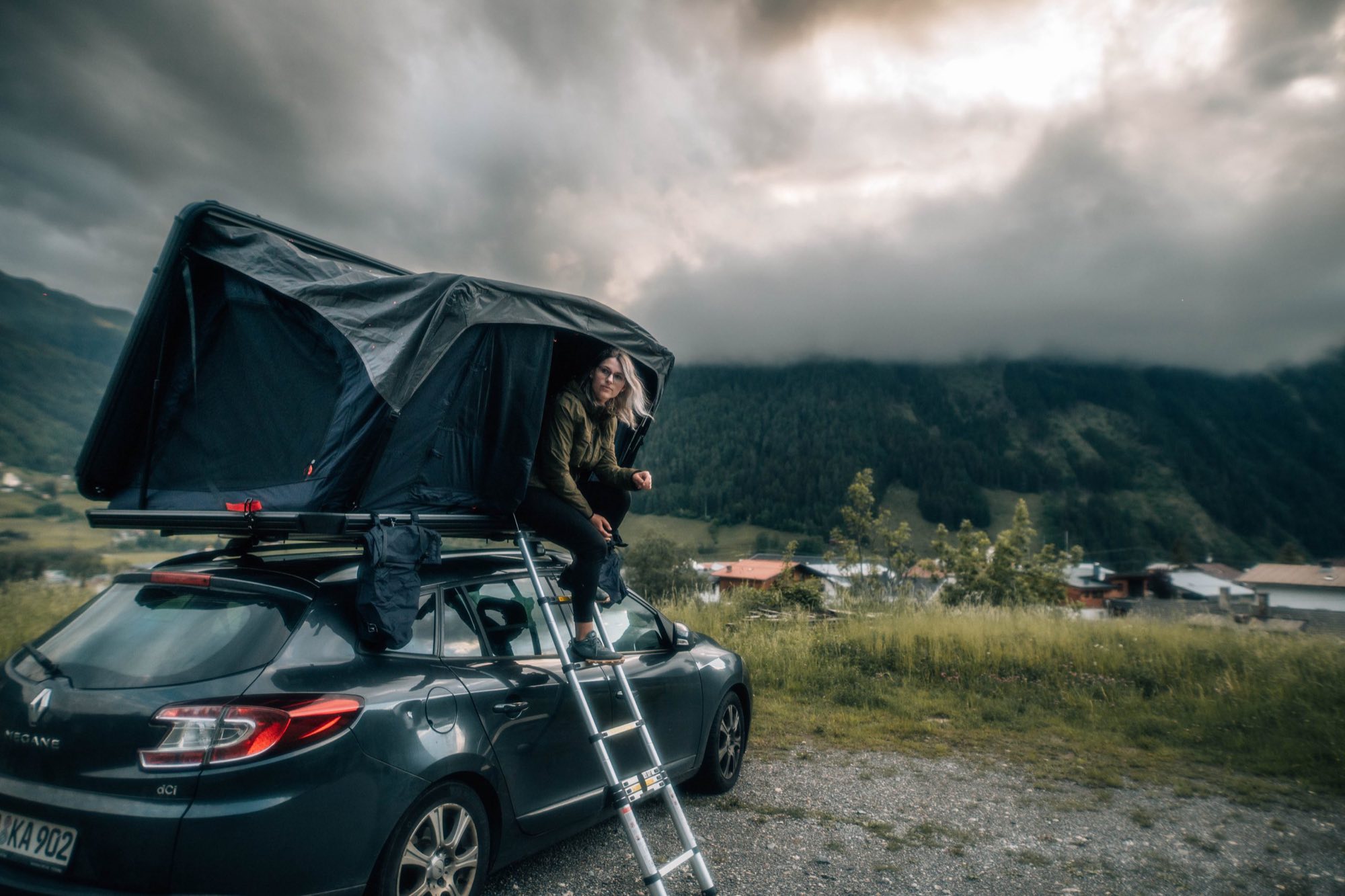 Auto mit aufgeklapptem Dachzelt vor Bergkulisse